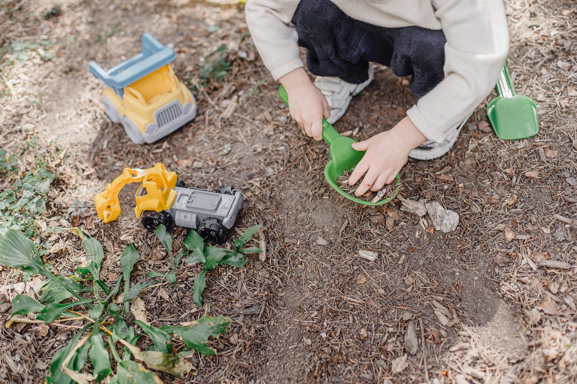 little kid playing in garden with toys